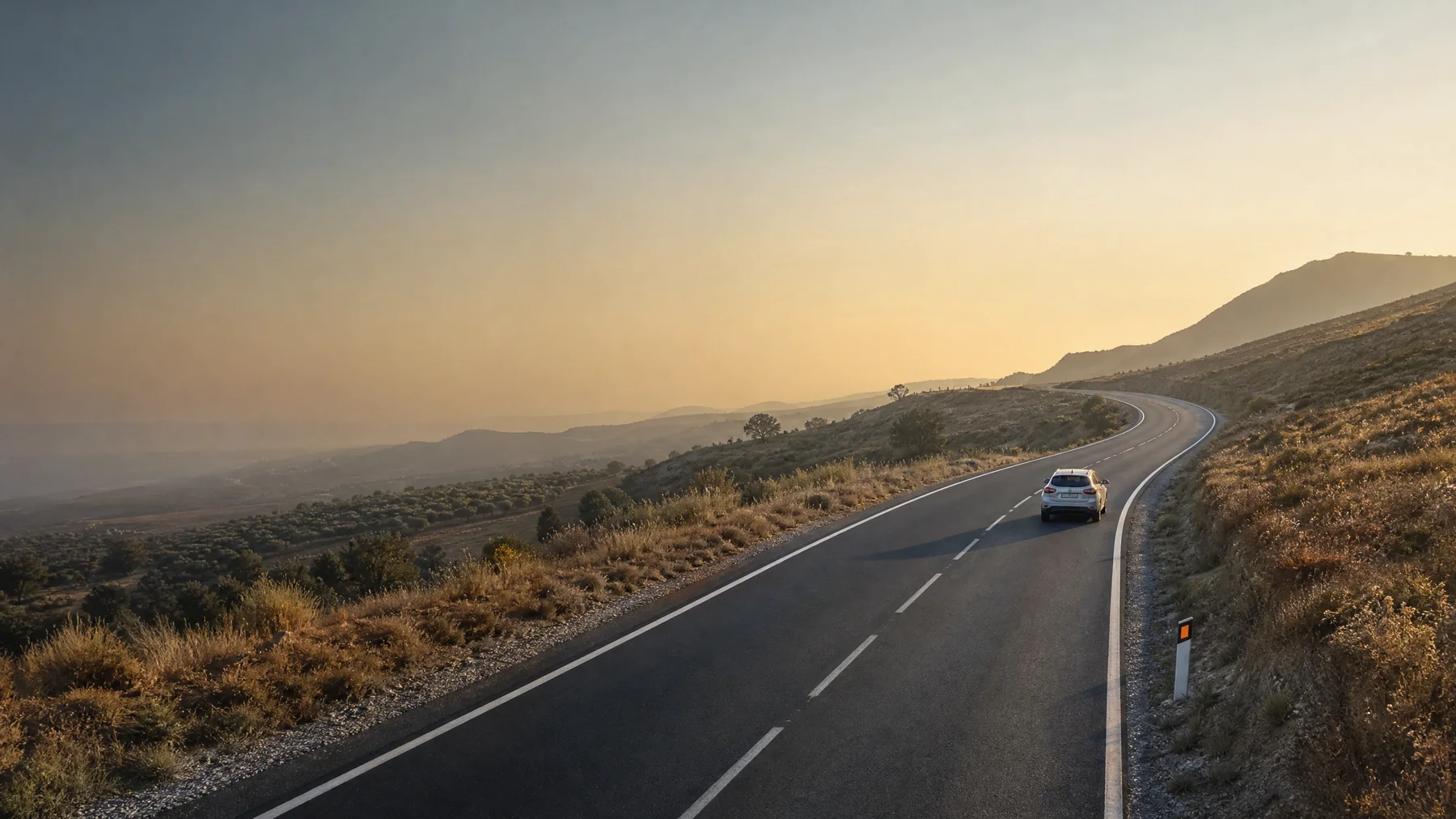 Carretera de dos carriles atravesando un paisaje mediterráneo